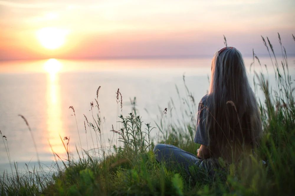 A woman watching the sunset beside the water